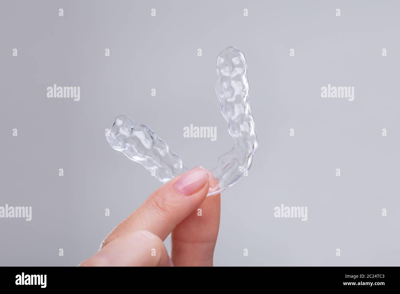 Close-up Of Woman's Hand Holding Transparent Plastic Braces Over Gray ...