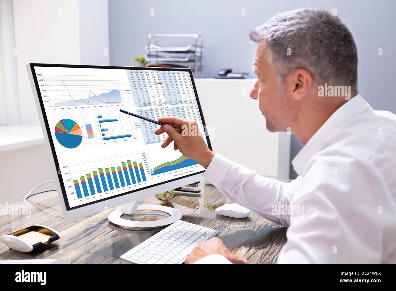 Businessman Analyzing Graphs On Computer At Workplace Stock Photo