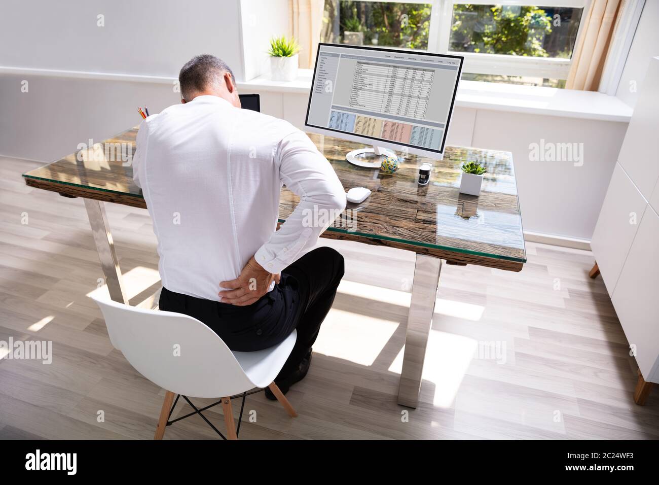 Businessman Suffering From Back Pain At Office Desk Stock Photo - Alamy