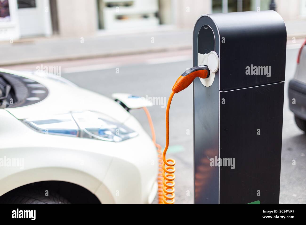 Power supply for electric car charging. Electric car charging station. Close up of the power supply plugged into an electric car being charged. Stock Photo