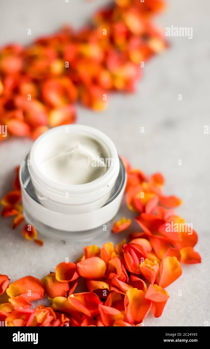 Beauty face moisturizing cream and flower petals on marble, luxury cosmetic product Stock Photo