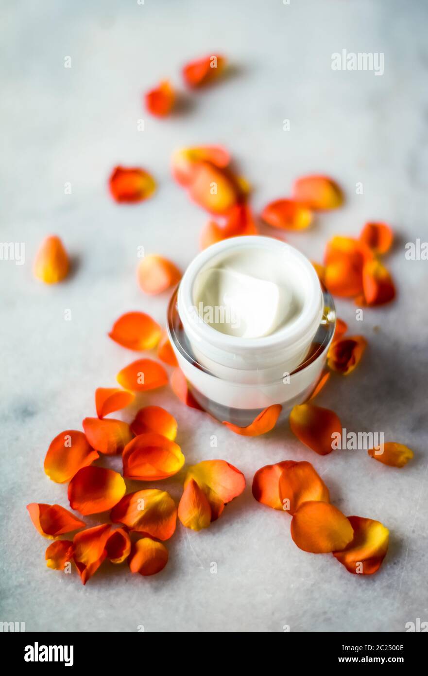 Beauty face moisturizing cream and flower petals on marble, luxury cosmetic product Stock Photo