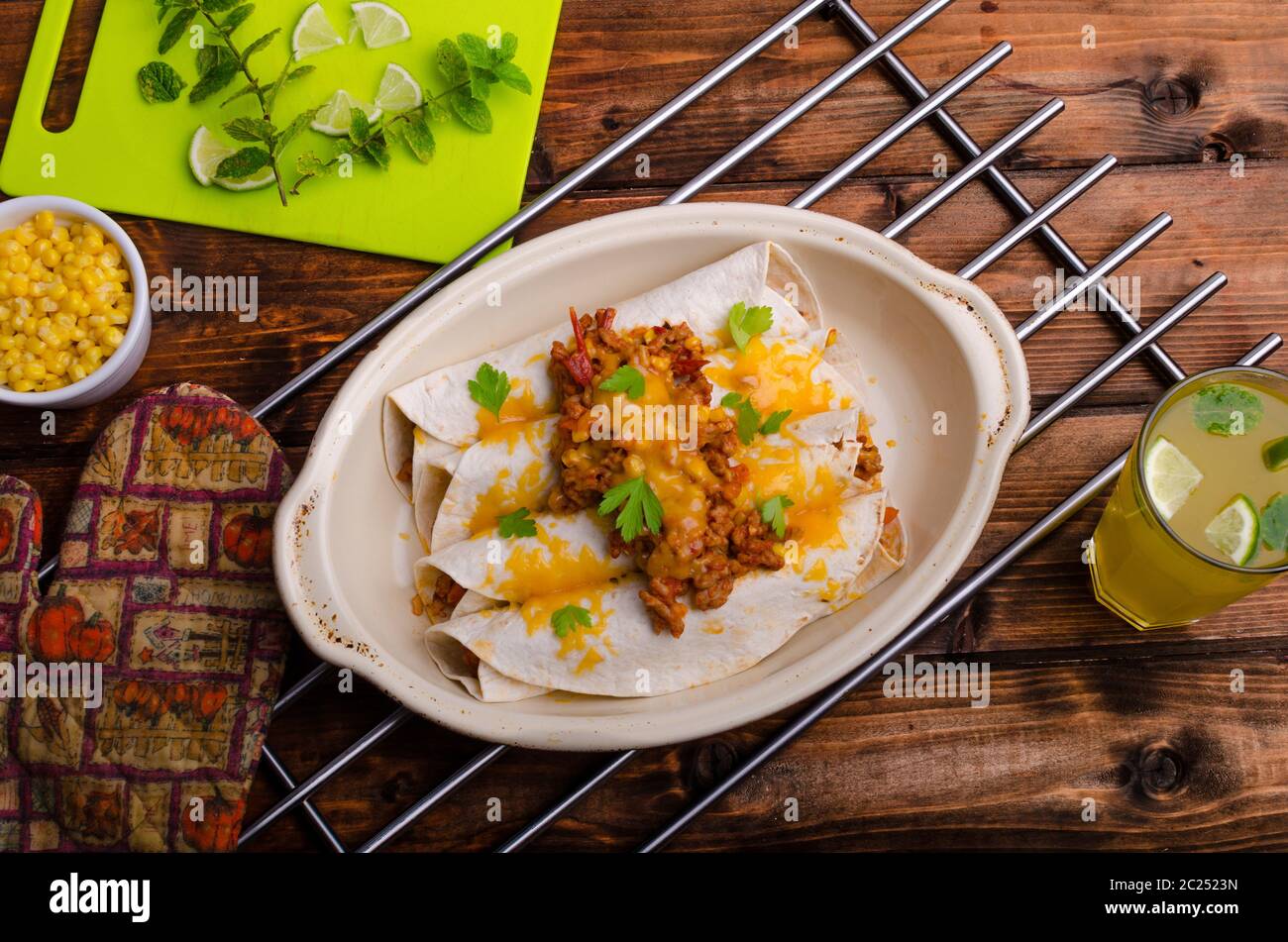 Baked meat tortilla with cheddar cheese, chilli peppers and corn, lime