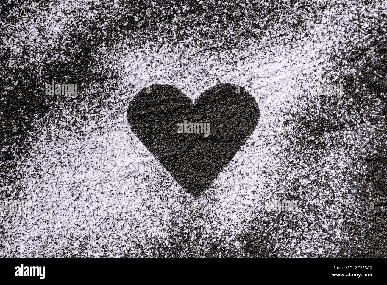 heart made of flour, icing sugar on black concrete Stock Photo