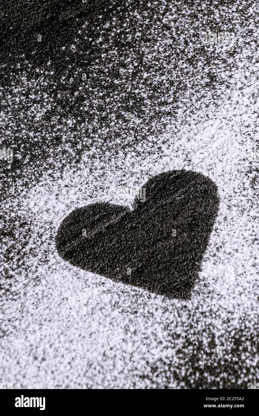 heart made of flour, icing sugar on black concrete Stock Photo