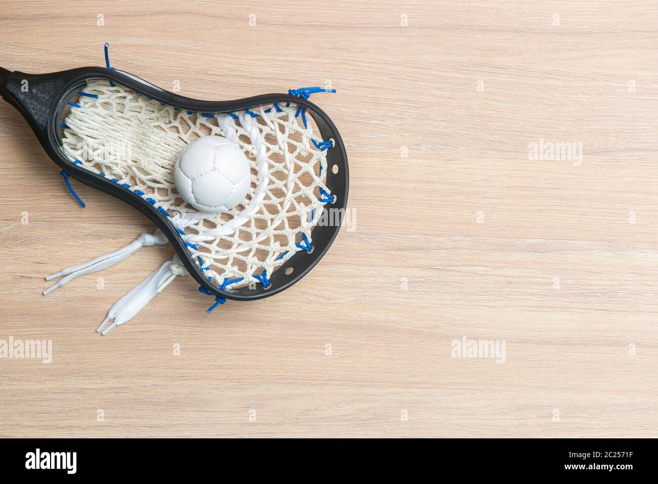 Lacrosse stick and white ball on wooden background. Lacross is a team sport Stock Photo