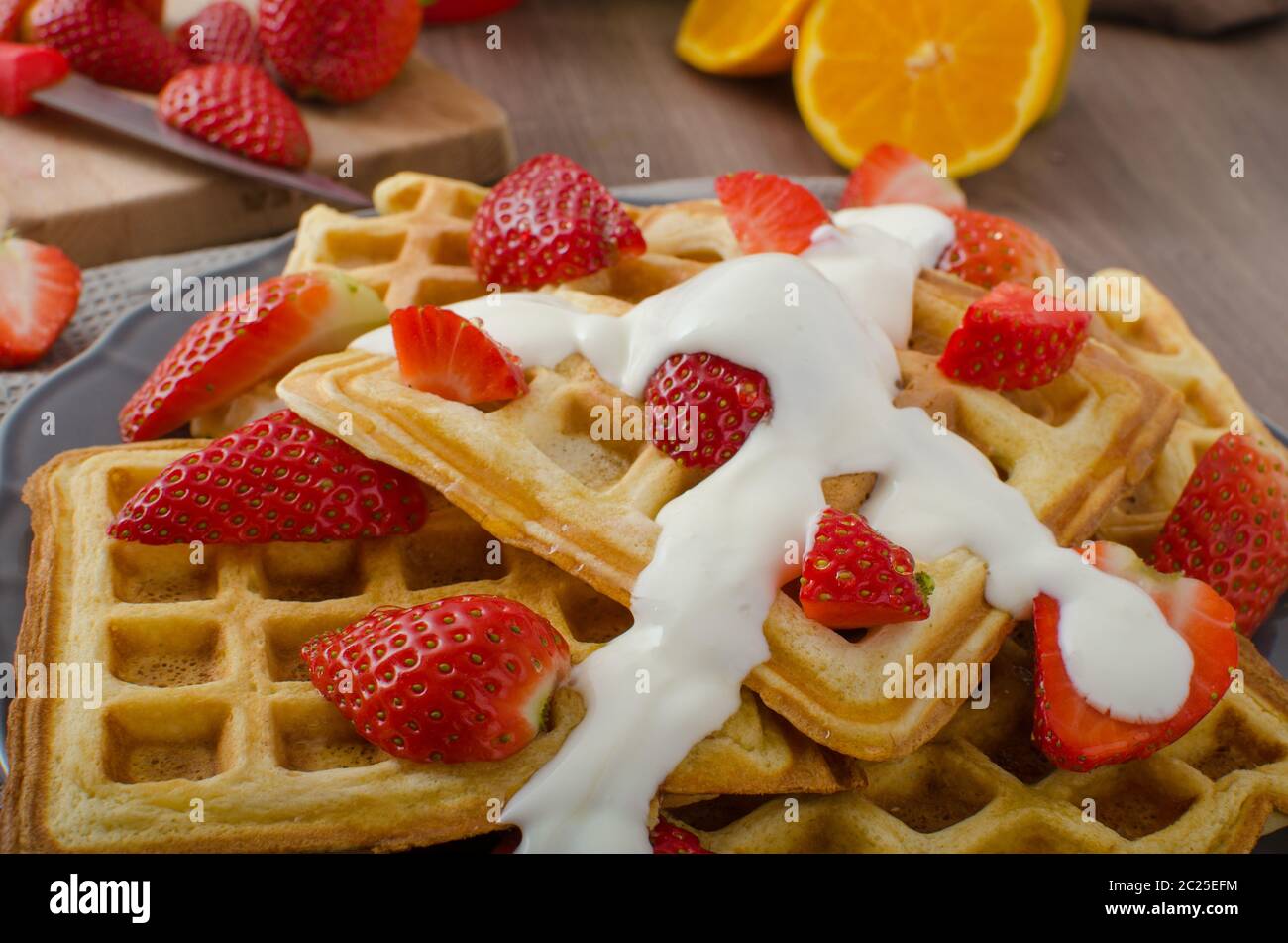 Homemade waffles with maple syrup and strawberries, topped fresh cream ...