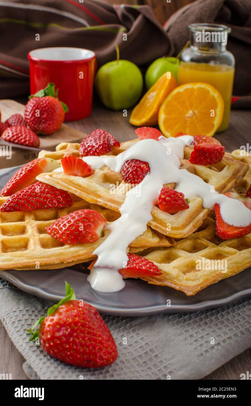 Homemade waffles with maple syrup and strawberries, topped fresh cream ...