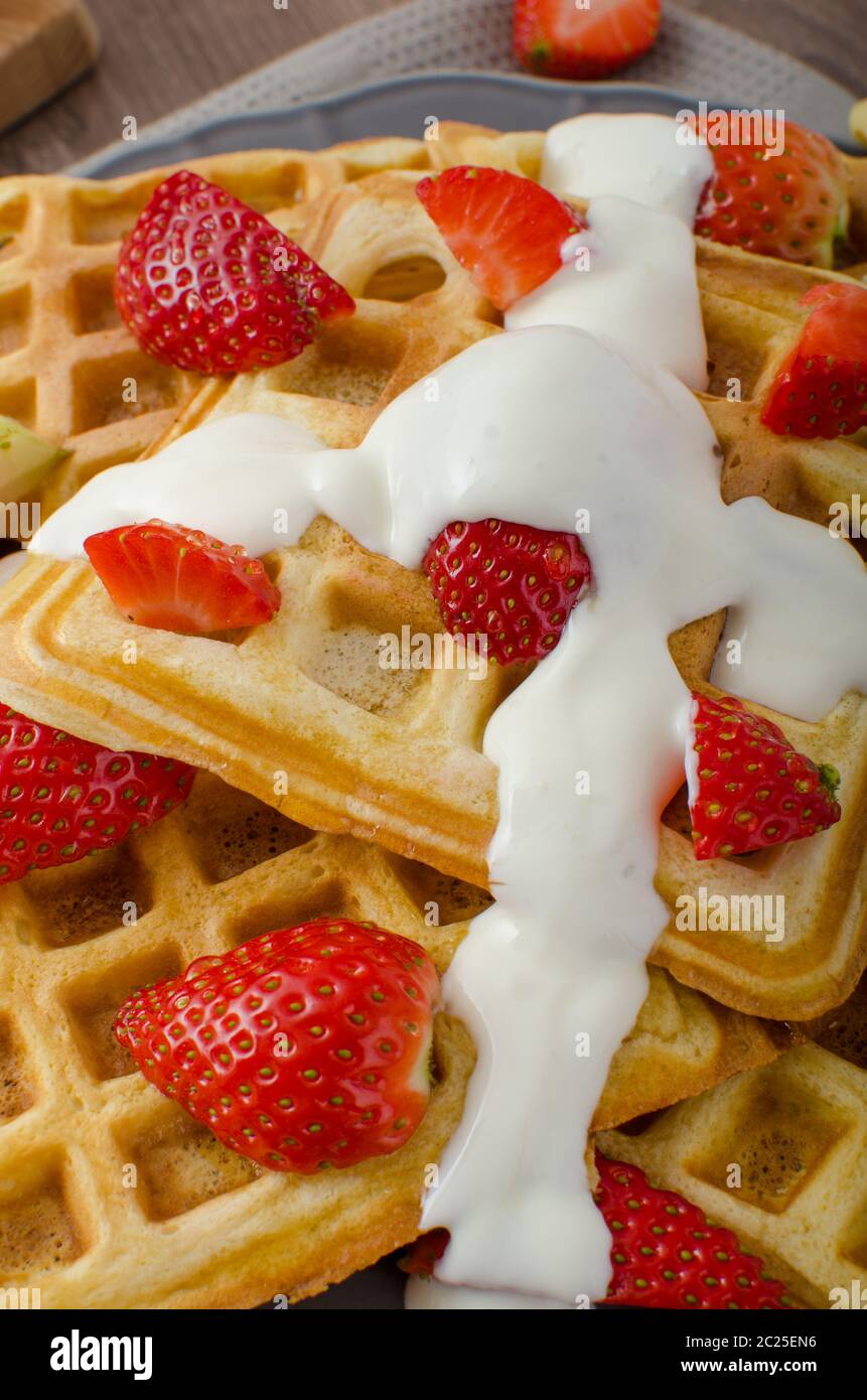 Homemade waffles with maple syrup and strawberries, topped fresh cream ...