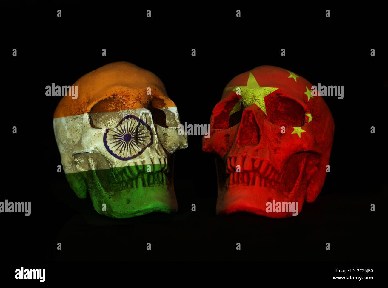 Chinese and india tension over shooting in disputed border territory. Two realsitic looking skulls face off with national flags of both side projected Stock Photo