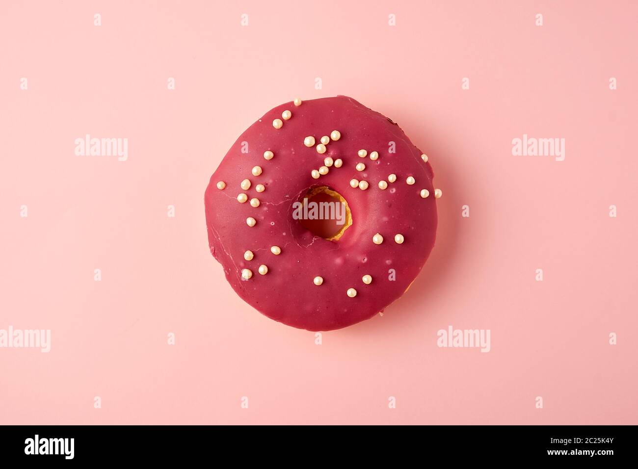 red round donut with white sprinkles on a pink background, top view Stock Photo