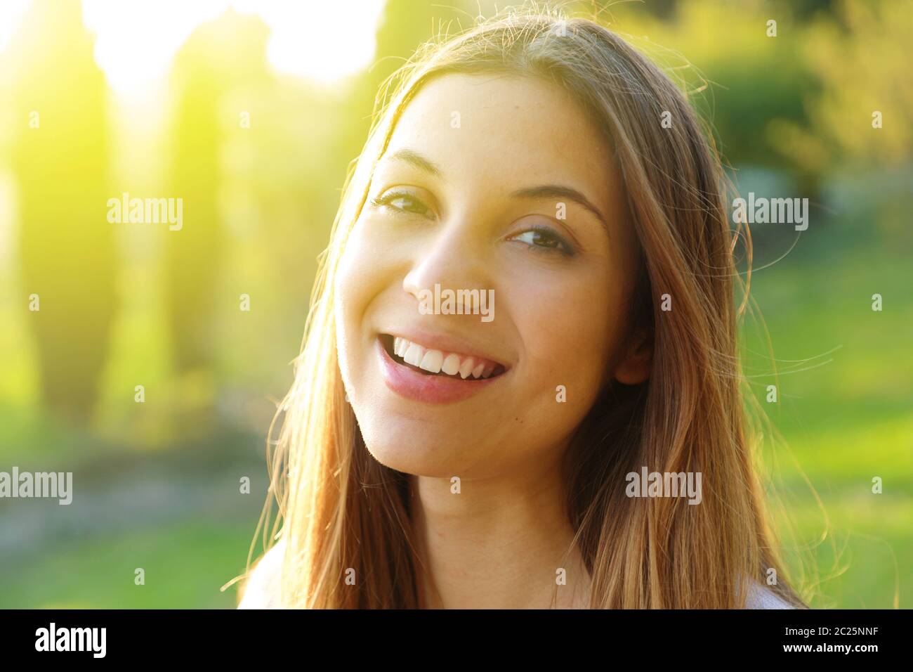 Portrait of smiling young woman with sunlight flare Stock Photo