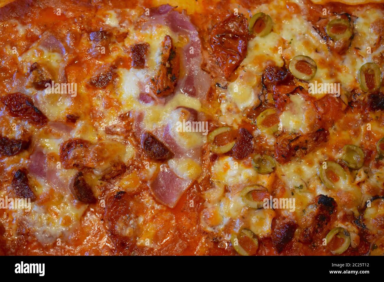 Home cooked half seafood half meat feast pizza. Octopus carpaccio mozzarella stuffed olives bacon spicy chorizo sausage all with melted cheese on top. Stock Photo