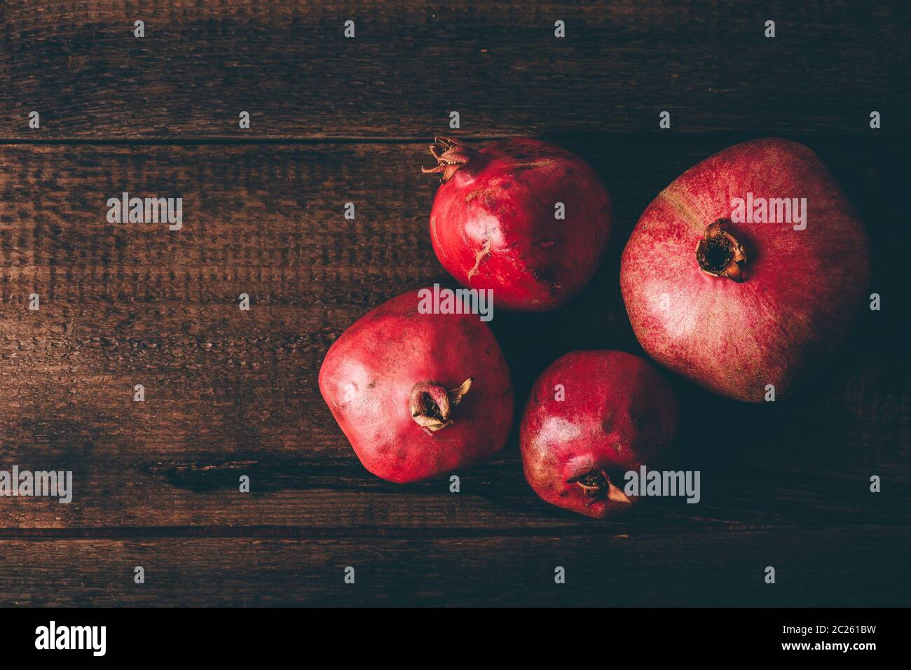 Four ripe pomegranate on rustic wooden table Stock Photo