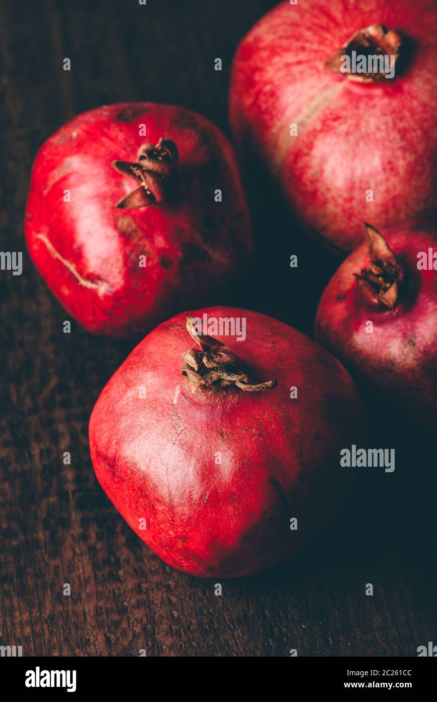 Four ripe pomegranate on rustic wooden table Stock Photo