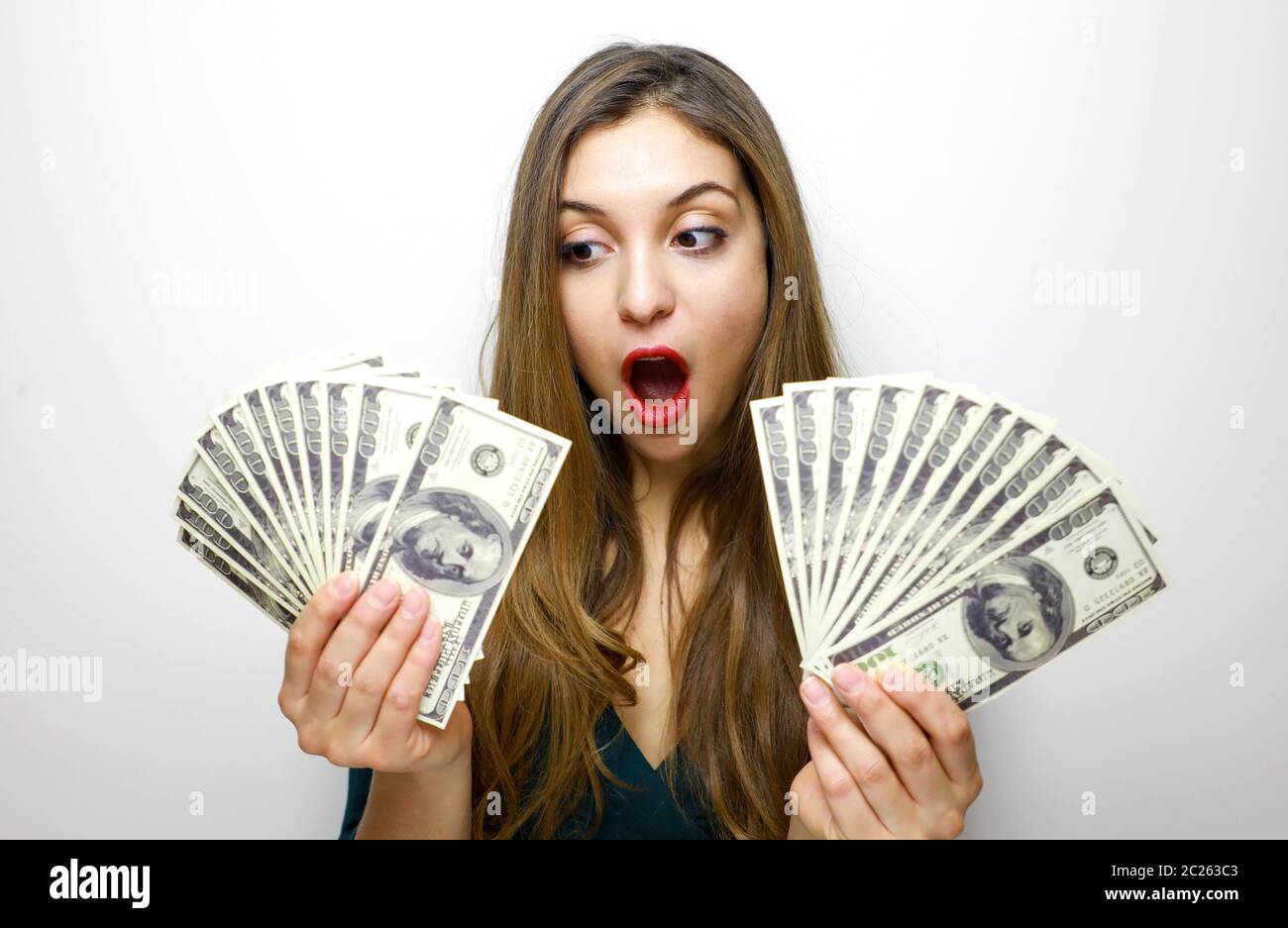 Portrait of a cheerful pretty girl looking at bunch of money banknotes ...