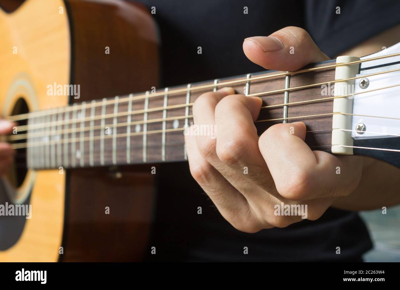 Guitar Player Hand or Musician Hand in C Major Chord on Acoustic Guitar String with soft natural light in side view Stock Photo