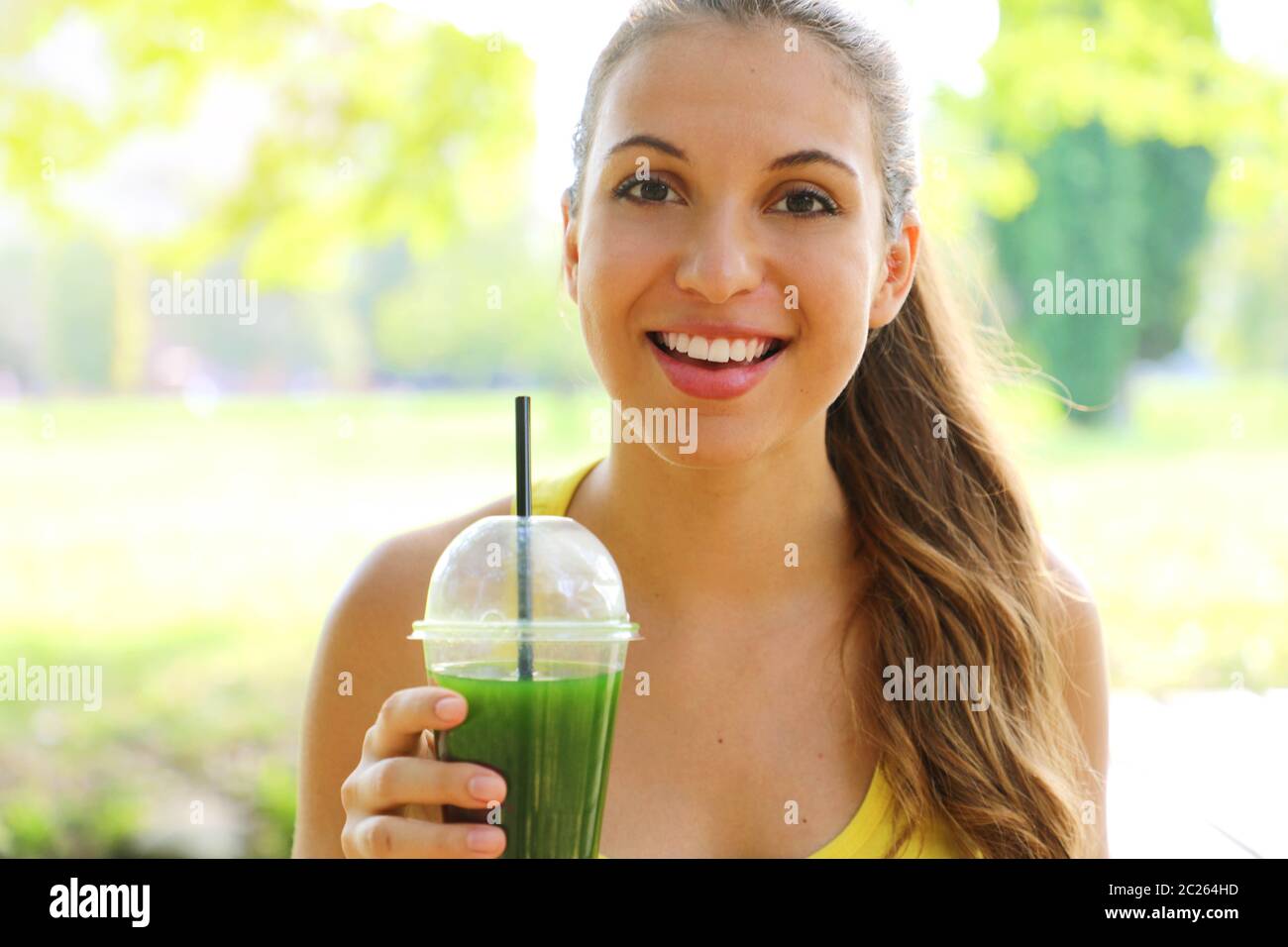Close up of fitness girl holding green detox juice in the park. Stock Photo