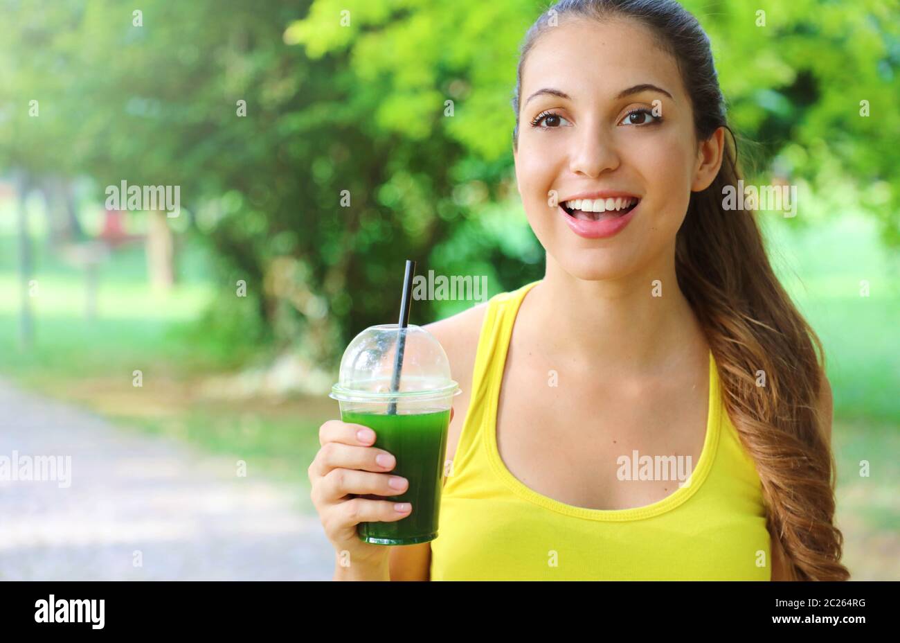 Excited fitness woman holding green detox smoothie and looking in front of her with copy space. Stock Photo