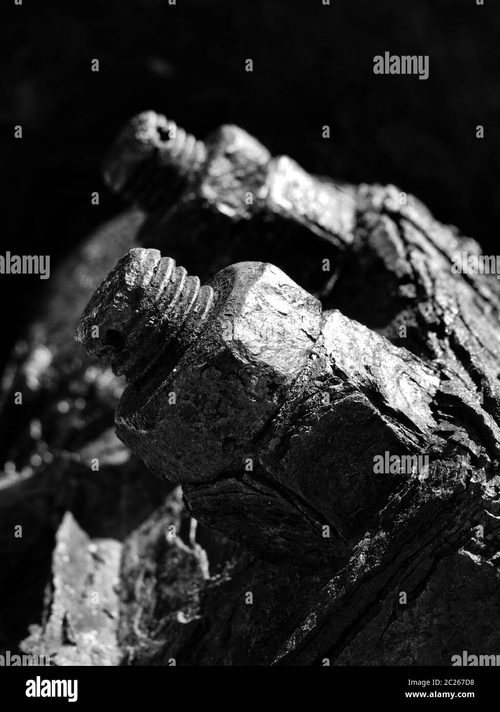 a monochrome close up of rusted threaded bolts and nuts on old corroded machinery Stock Photo