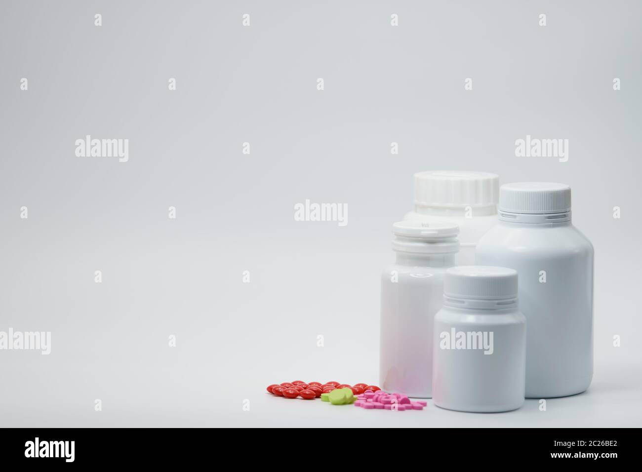 https://c8.alamy.com/comp/2C26BE2/pink-green-and-red-tablets-on-white-background-with-drug-bottle-container-light-resistant-packaging-pharmaceutical-industry-vitamin-and-supplemen-2C26BE2.jpg