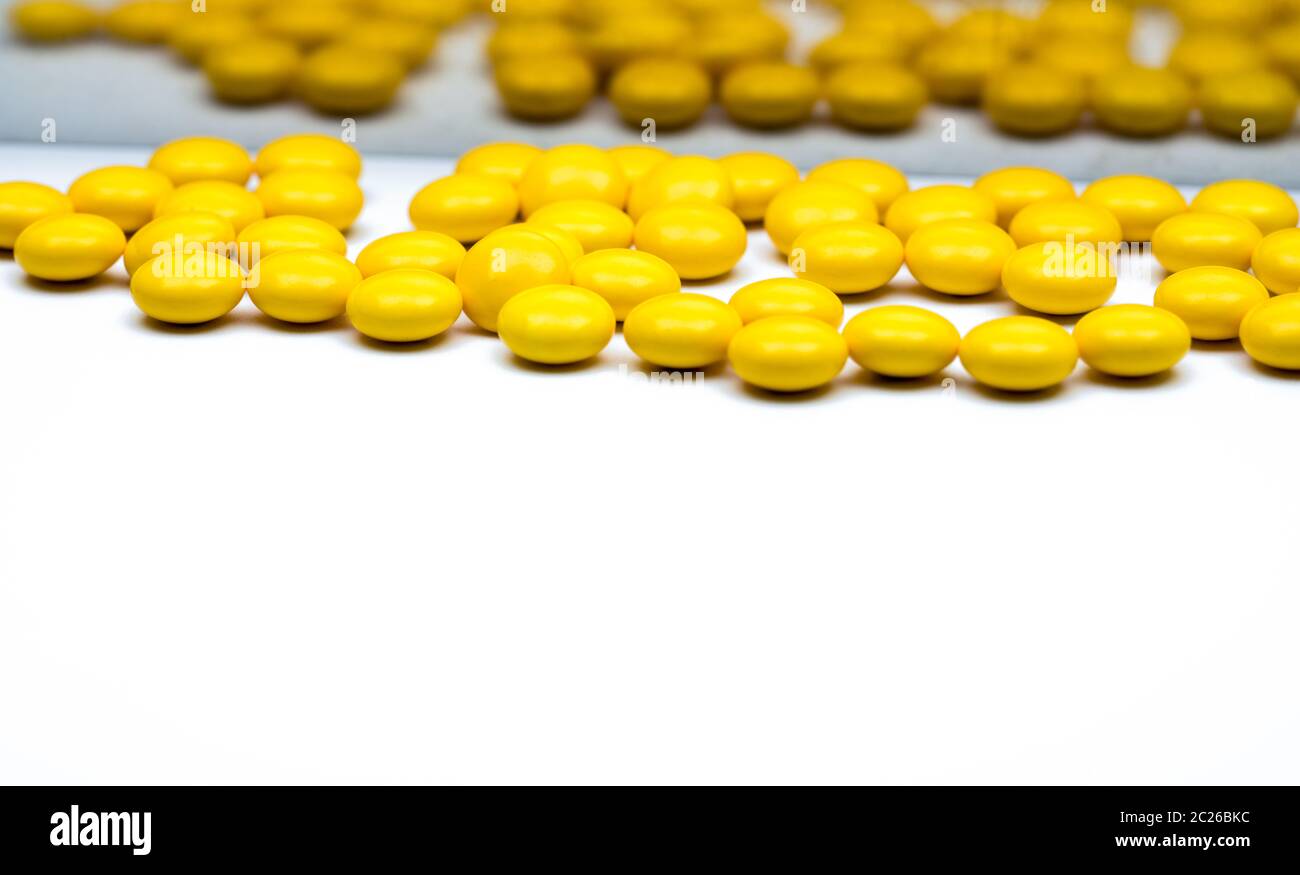 Macro shot detail of yellow round sugar coated tablets pills on blurred tablets pills background with copy space for text. Stock Photo