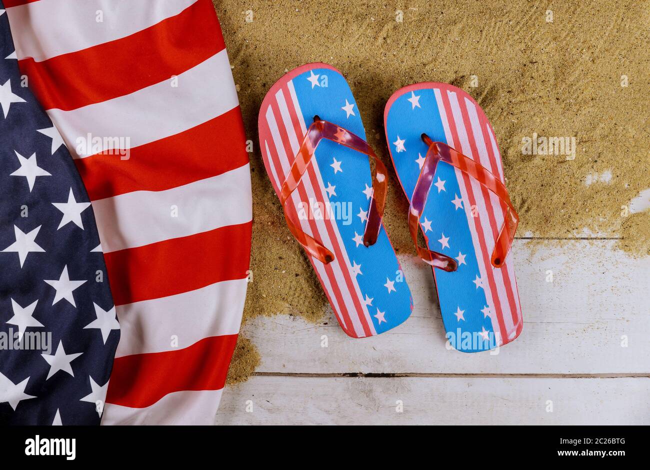View of beach sand with American flag beach slippers flip flops summer season vacation Stock Photo