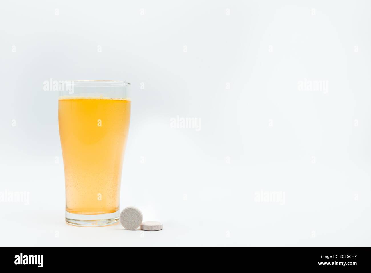 Two effervescent tables on white background and orange effervescent bubbles of calcium and vitamin C effervescent tablets in transparent glass. Vitami Stock Photo