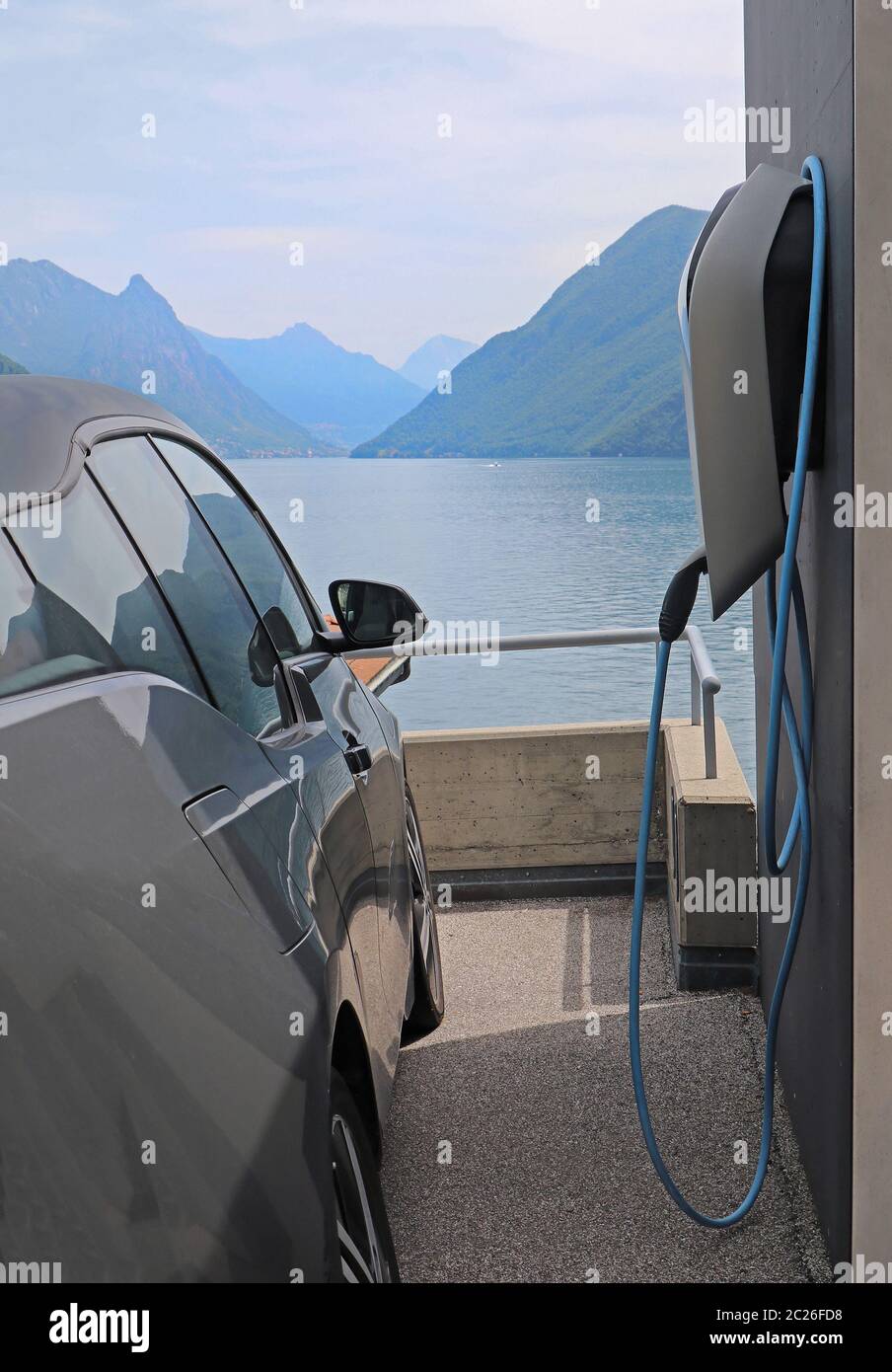 Small electric city car parked next to charging station Stock Photo