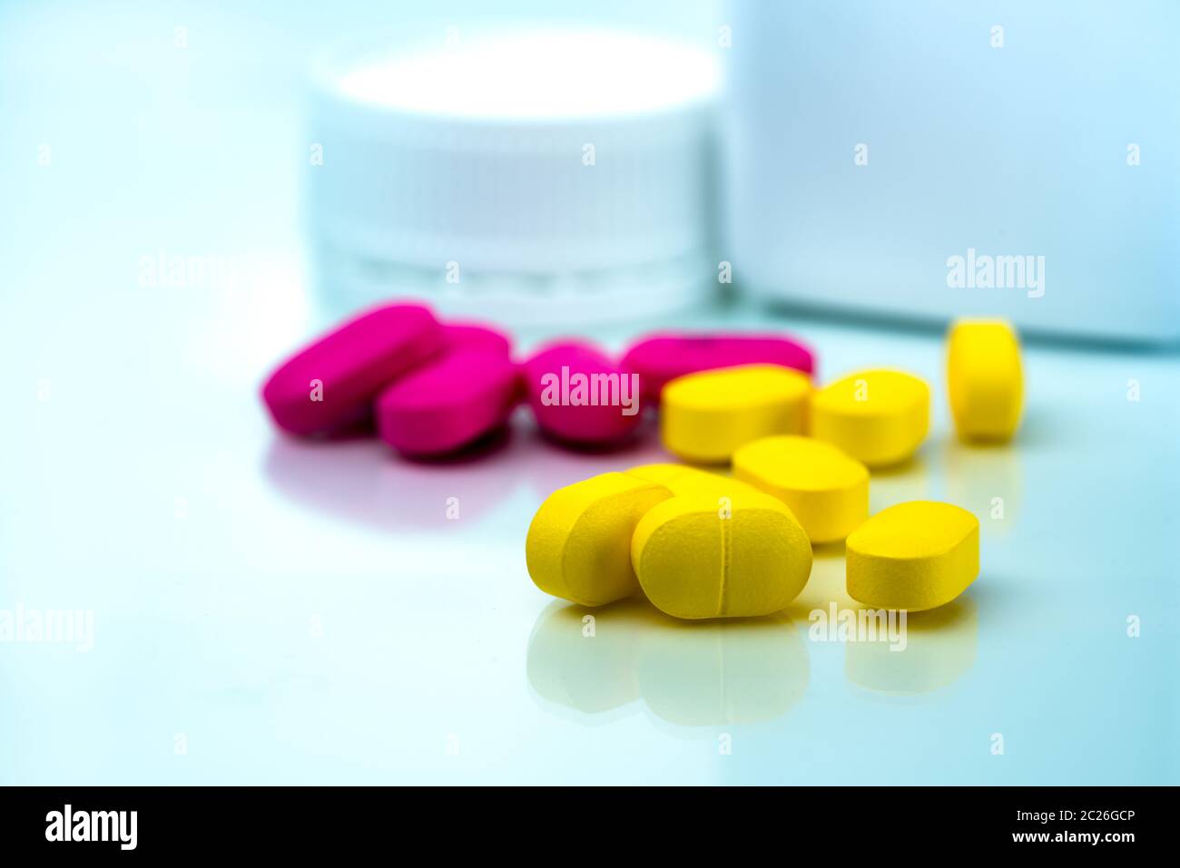 Pile of yellow and pink tablets pills on blurred background of plastic