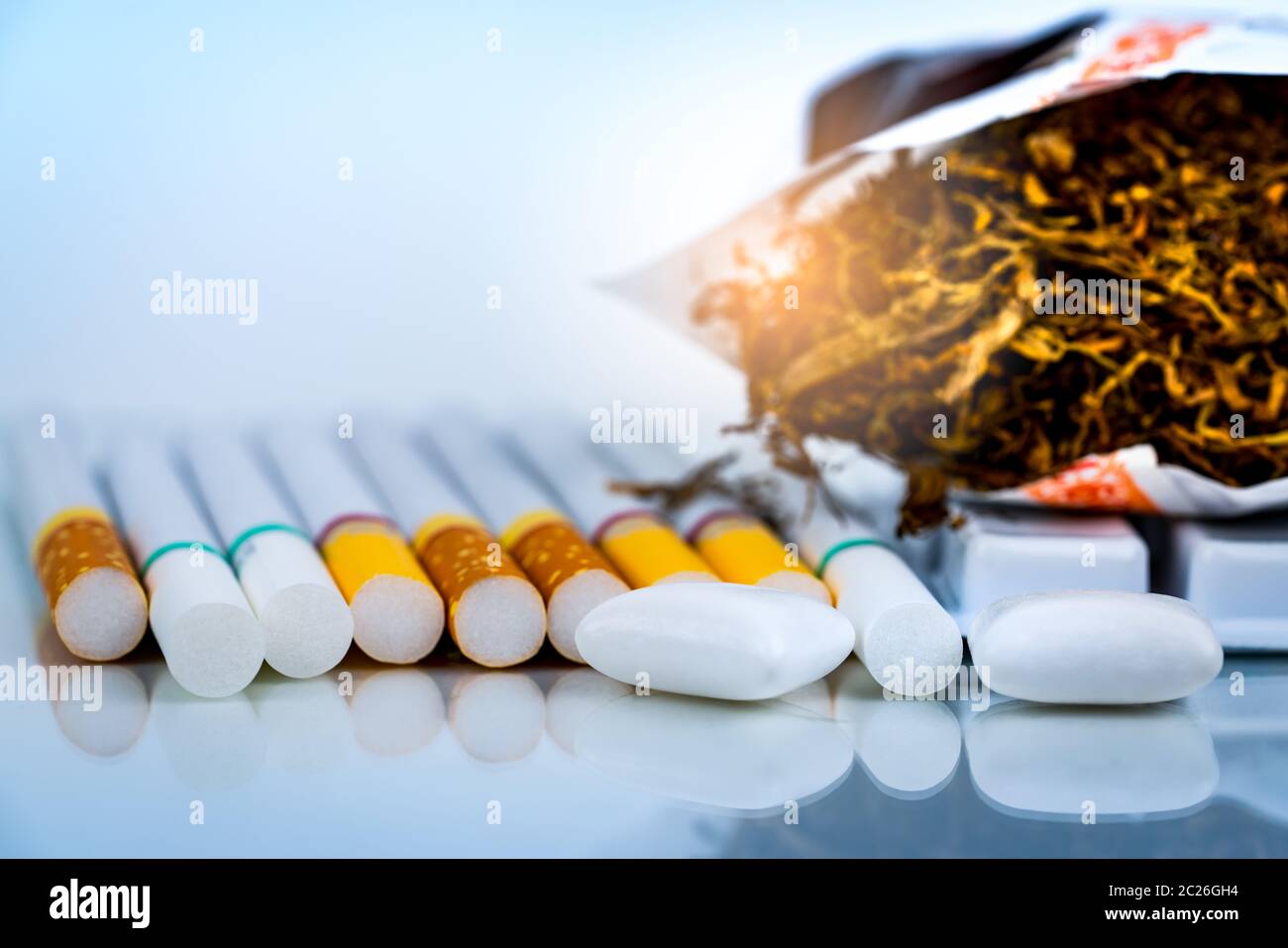 Nicotine chewing gum near pile of cigarettes and tobacco on white background with space. Quit