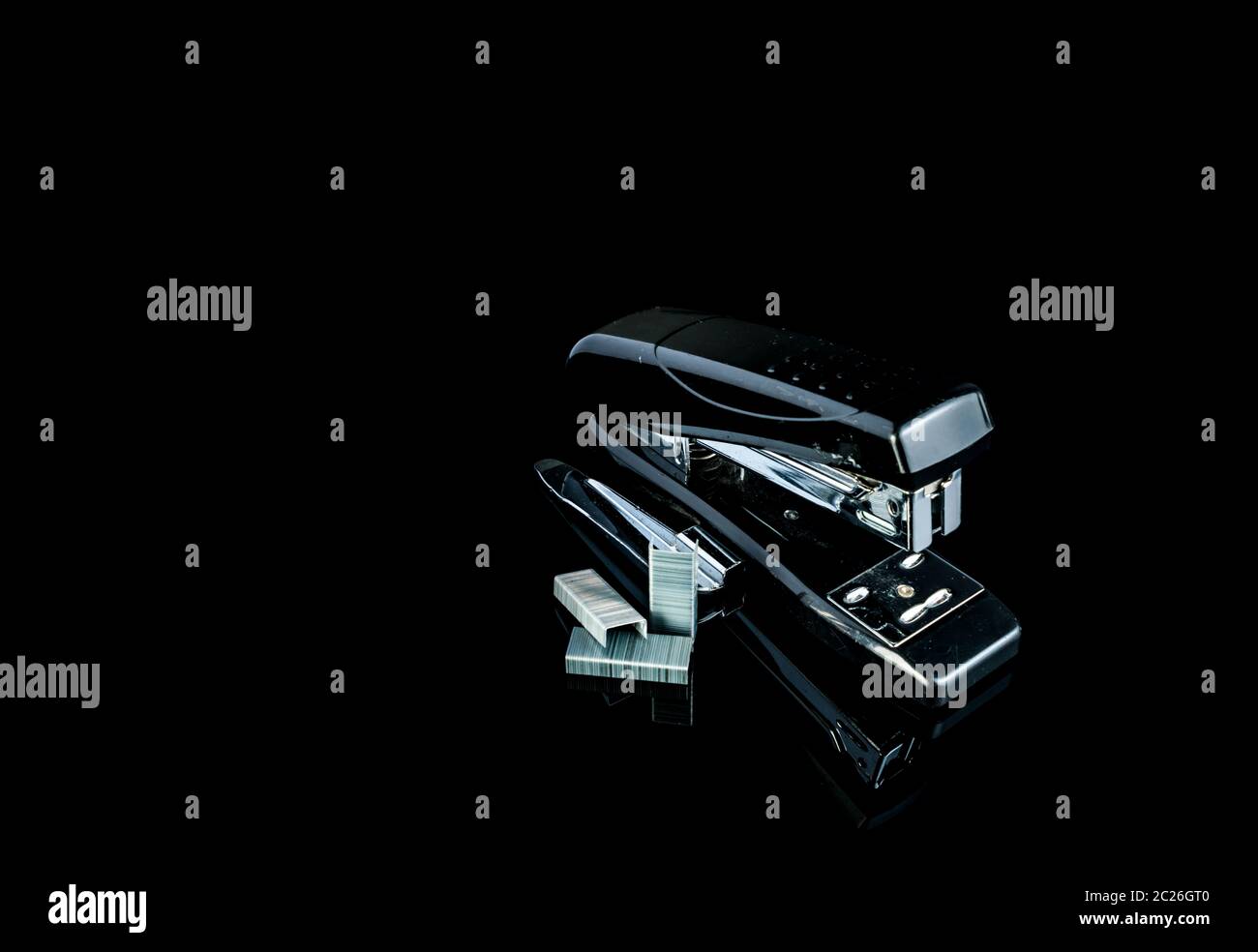 Black stapler and staples on dark background. Stock Photo