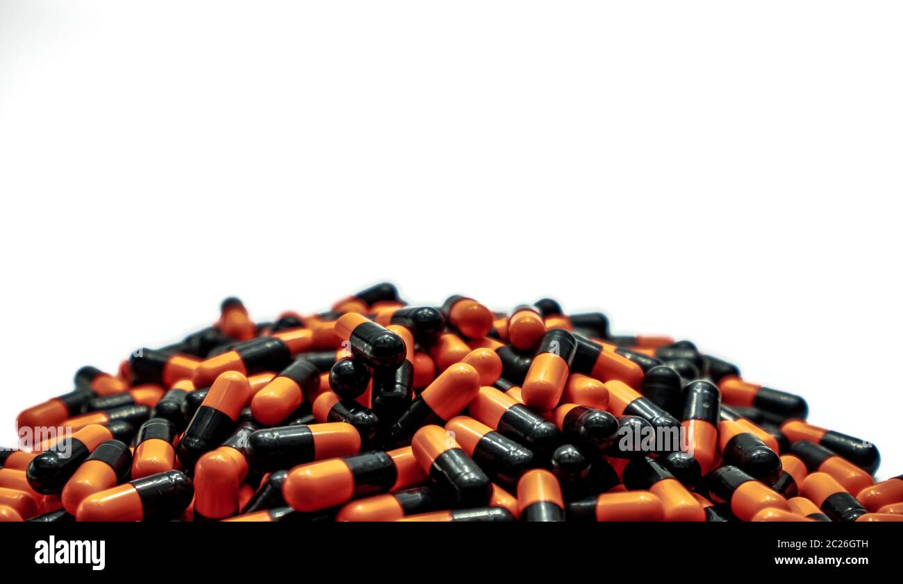 Pile of black and orange antibiotic capsule pills isolated on white