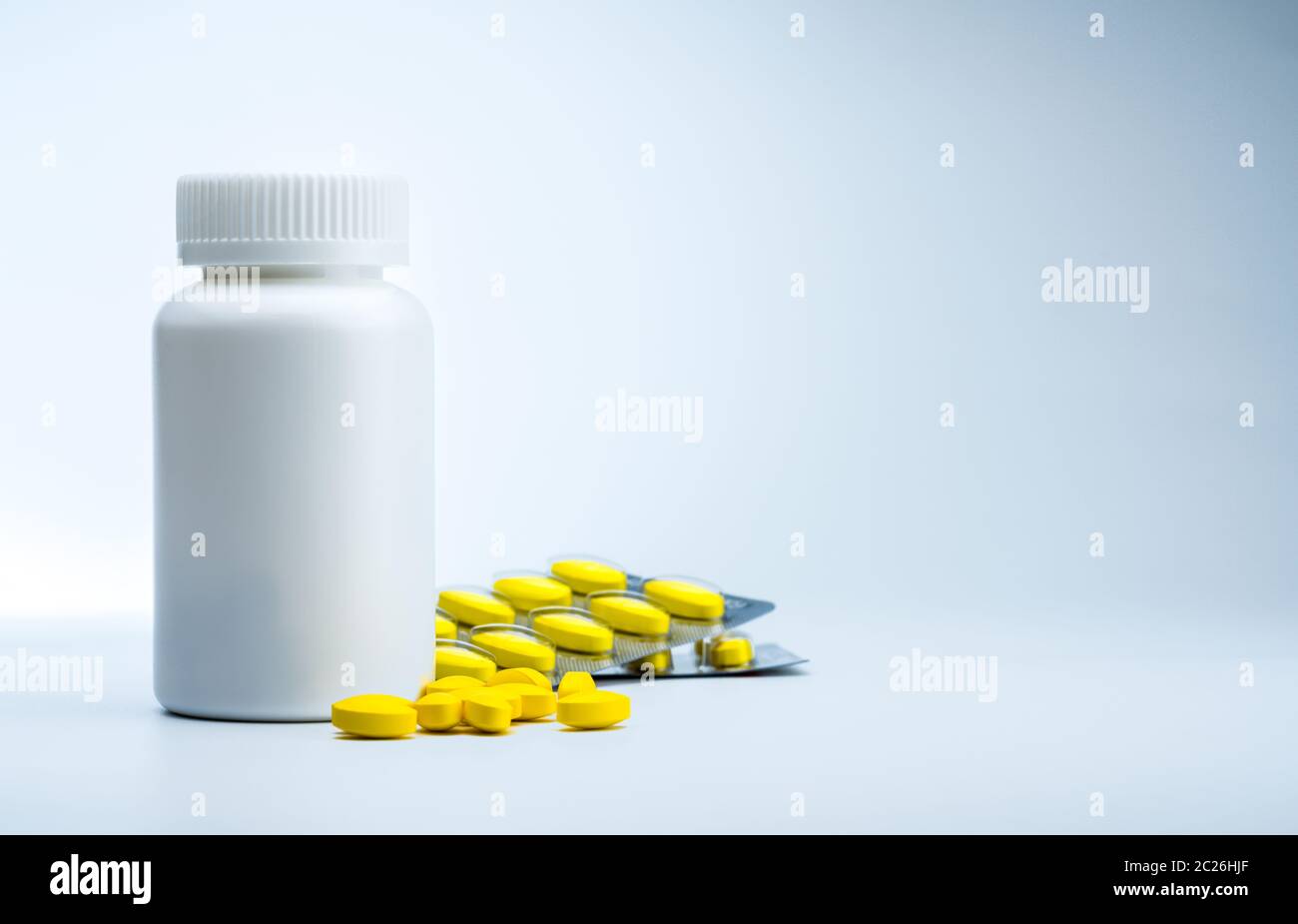 Yellow oval tablet pills and plastic bottle with blank label. Mild to