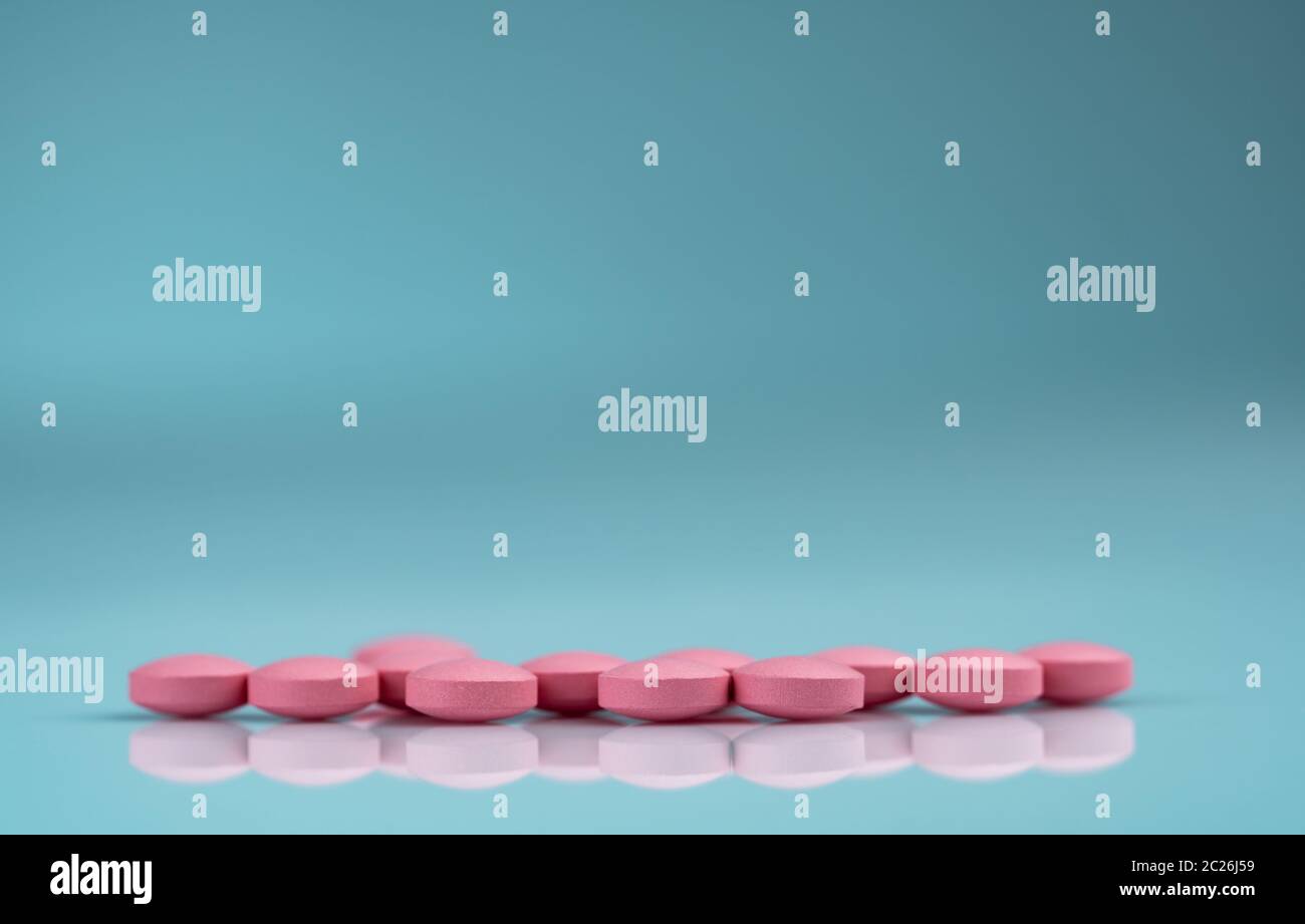 Round pink tablets pill on gradient background. Vitamins and minerals plus folic acid vitamin E and zinc in drug bottle on gradient background. Pink t Stock Photo