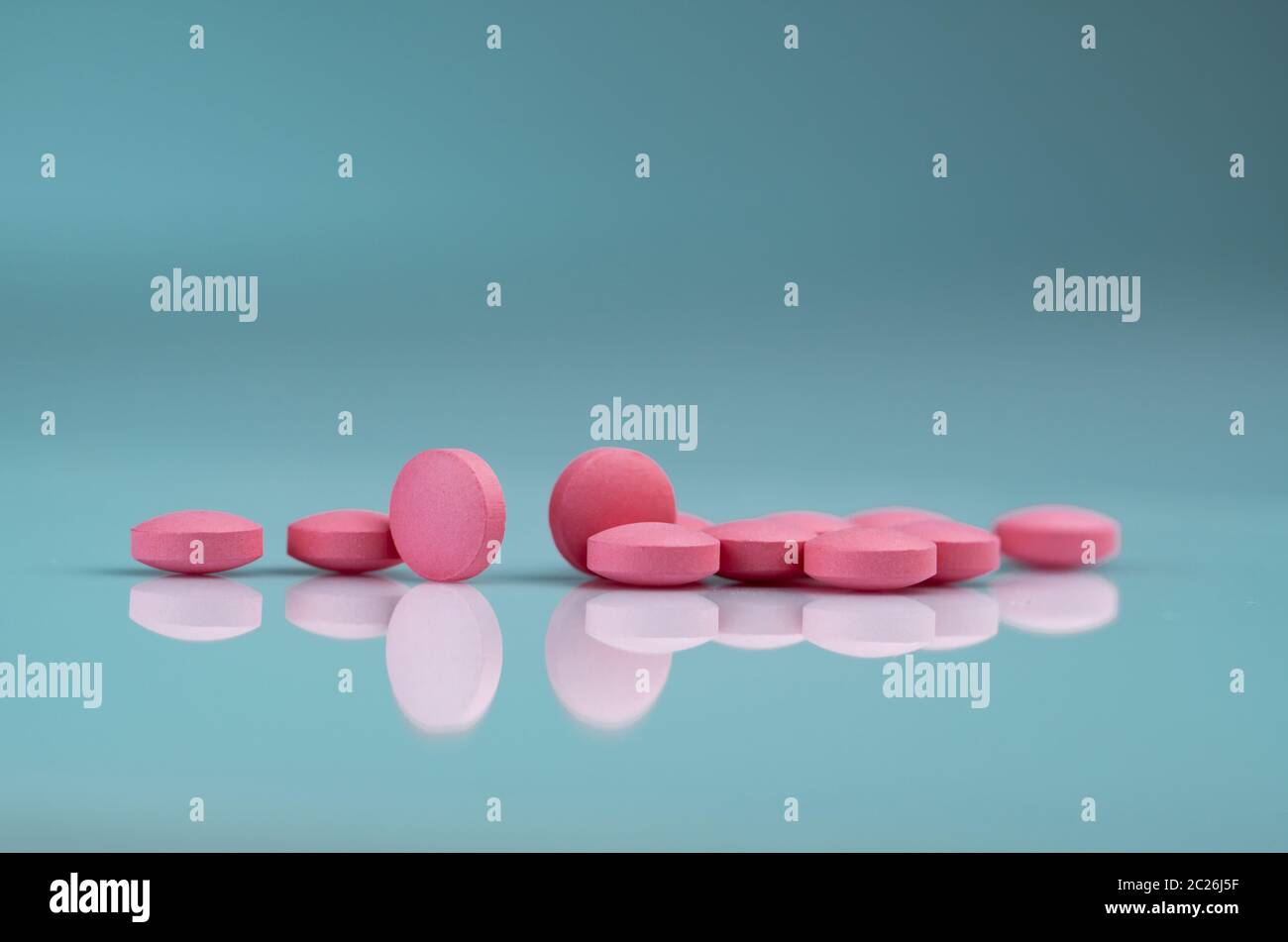Round pink tablets pill on gradient background. Vitamins and minerals plus folic acid vitamin E and zinc in drug bottle on gradient background. Pink t Stock Photo