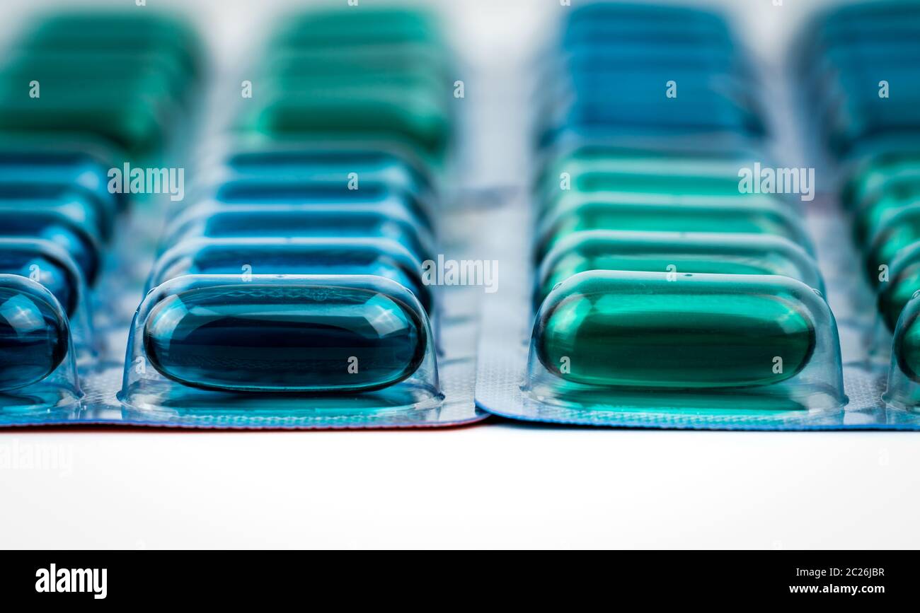 Selective focus on blue and green soft gel capsule pills in blister