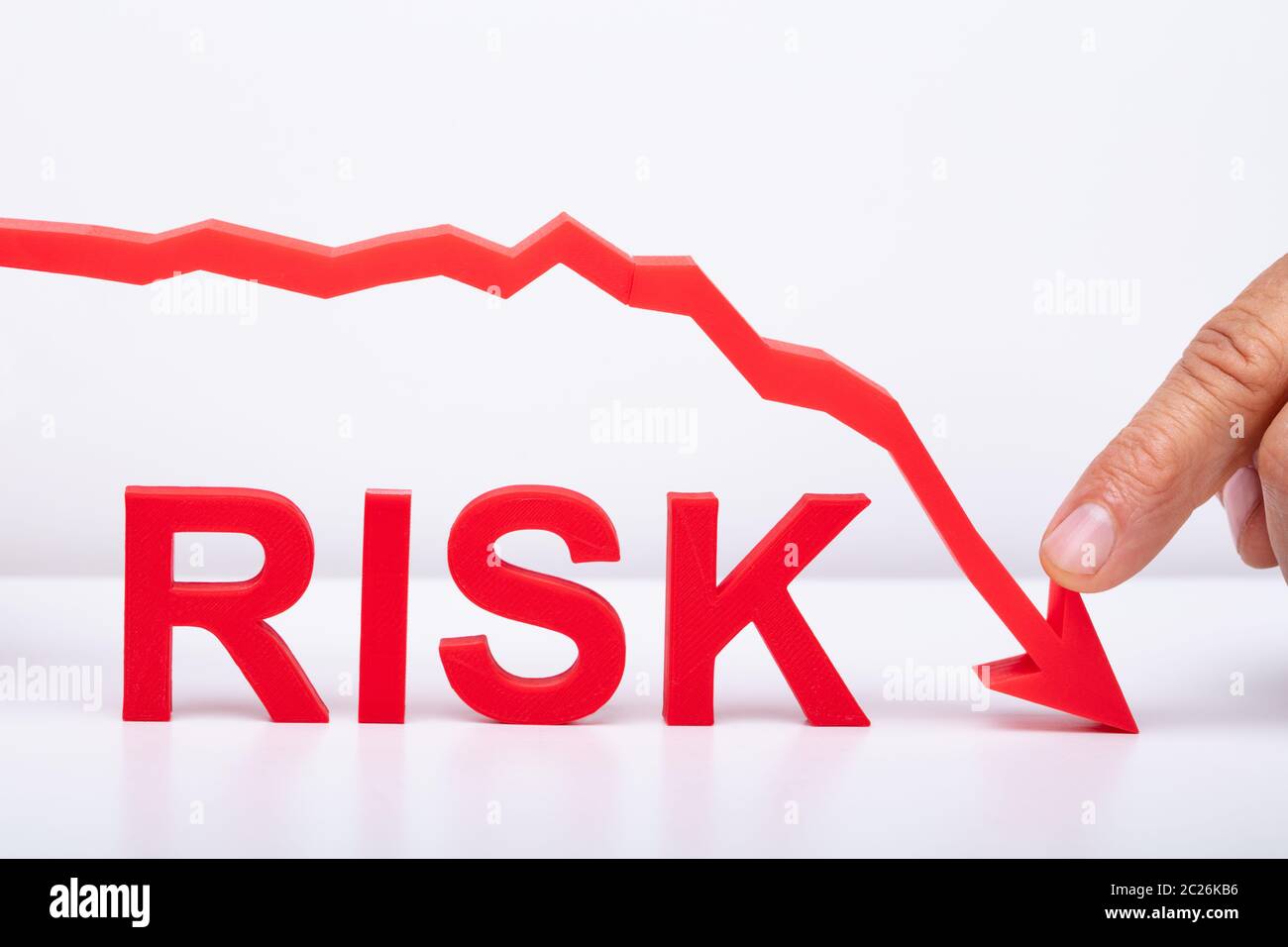 Businessman Pointing Red Diminishing Arrow Over The Risk Text On Desk Stock Photo