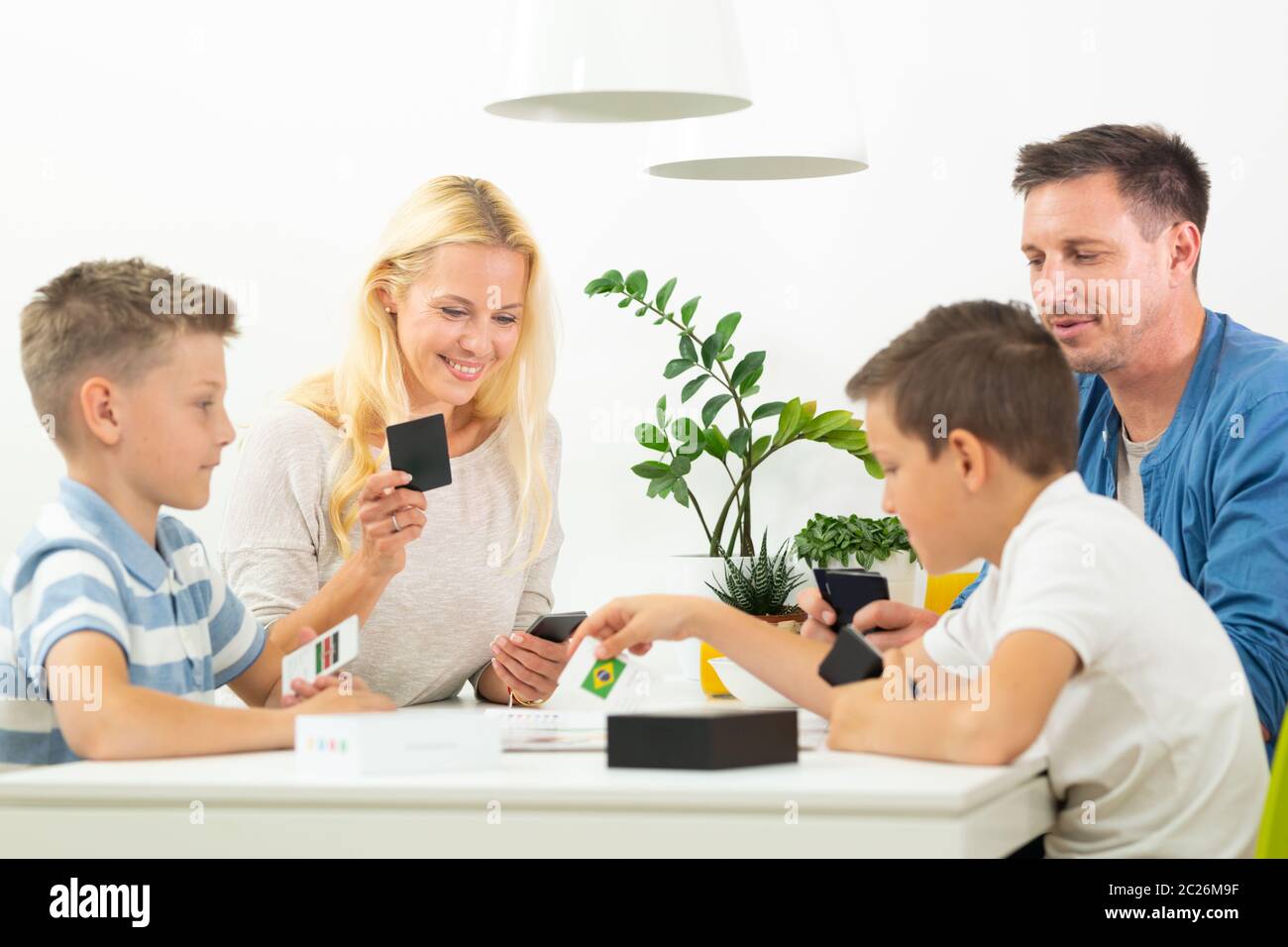 Happy young family playing card game at dining table at bright modern ...