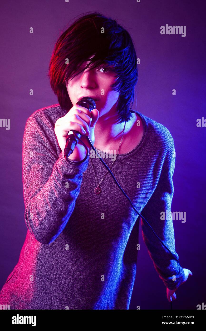 The young guy in emo style is singing in microphone. Stock Photo