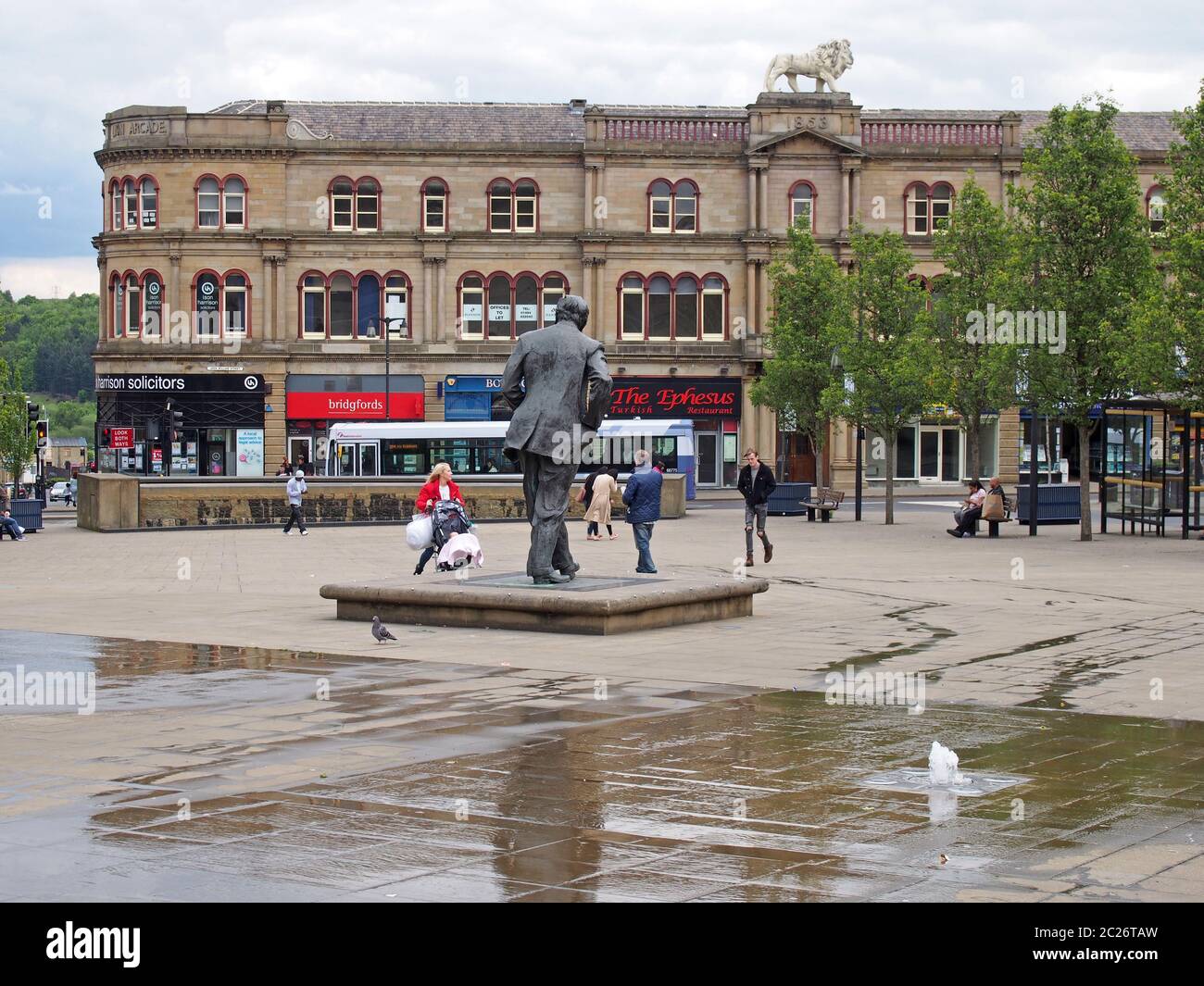 People walking in st georges square in Huddersfield between the water fountains and surrounding buildings Stock Photo