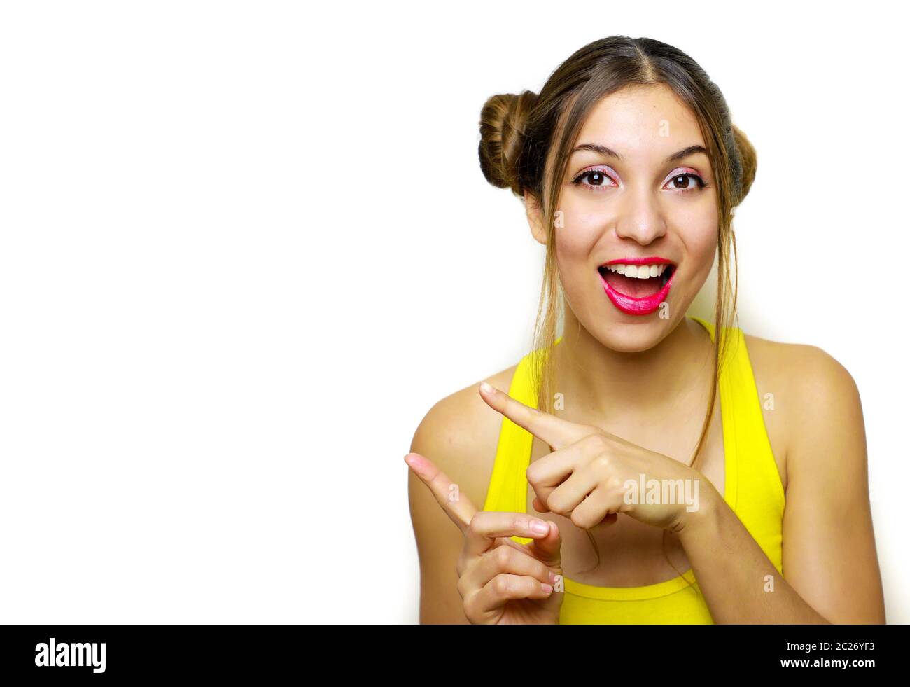 Attractive young woman with chignon pointing fingers copy space on white background Stock Photo
