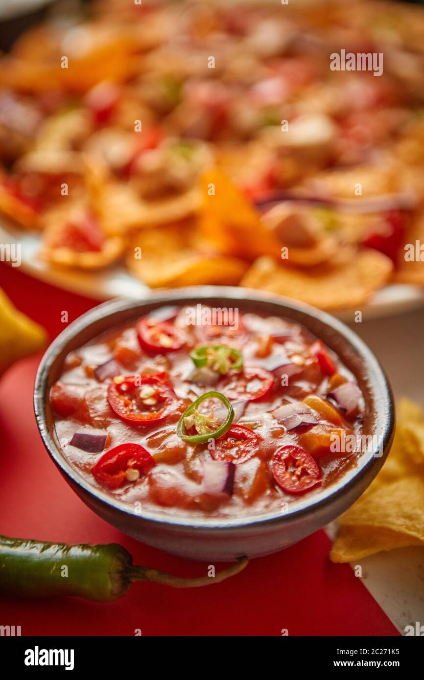 Close up on hot tomato dip in ceramic bowl with various freshly made Mexican foods Stock Photo
