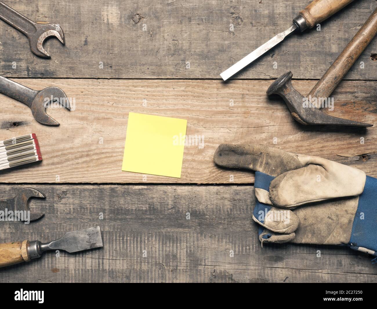 Old used tools with a sticky note on a workbench with space for text Stock Photo