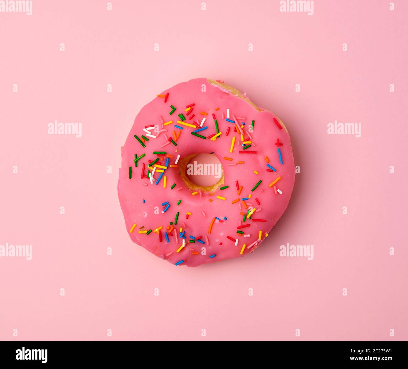 pink round donut with colored sprinkles on a pink background, top view Stock Photo