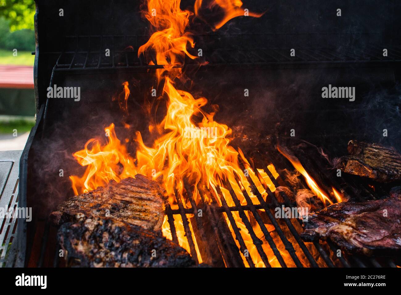 Meat cooking on a grill with flames Stock Photo - Alamy