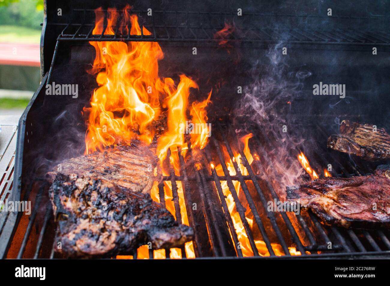 Meat cooking on a grill with flames Stock Photo - Alamy