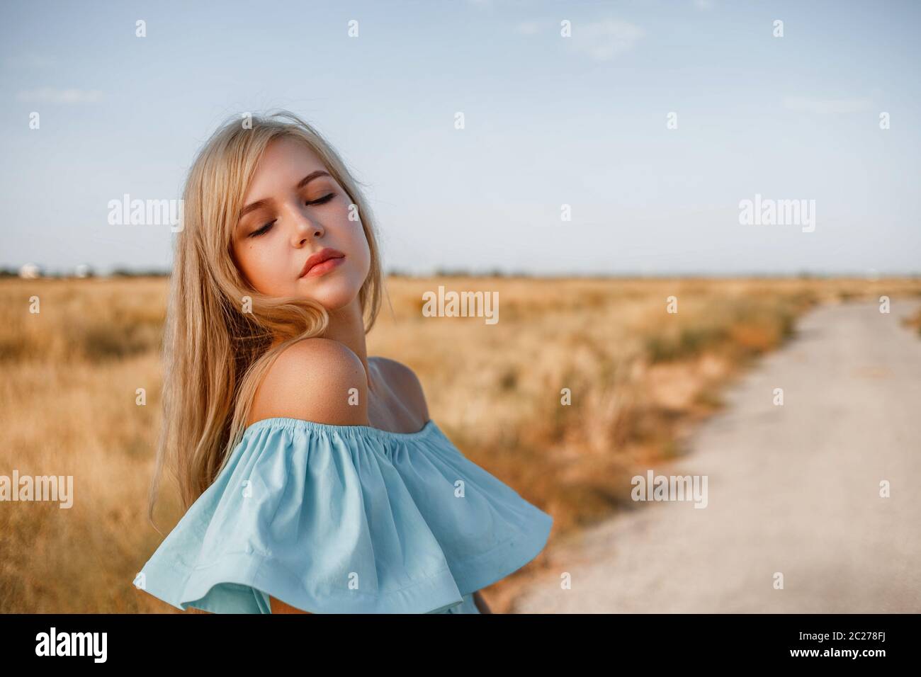 portrait of a young beautiful caucasian blonde girl in a light blue ...