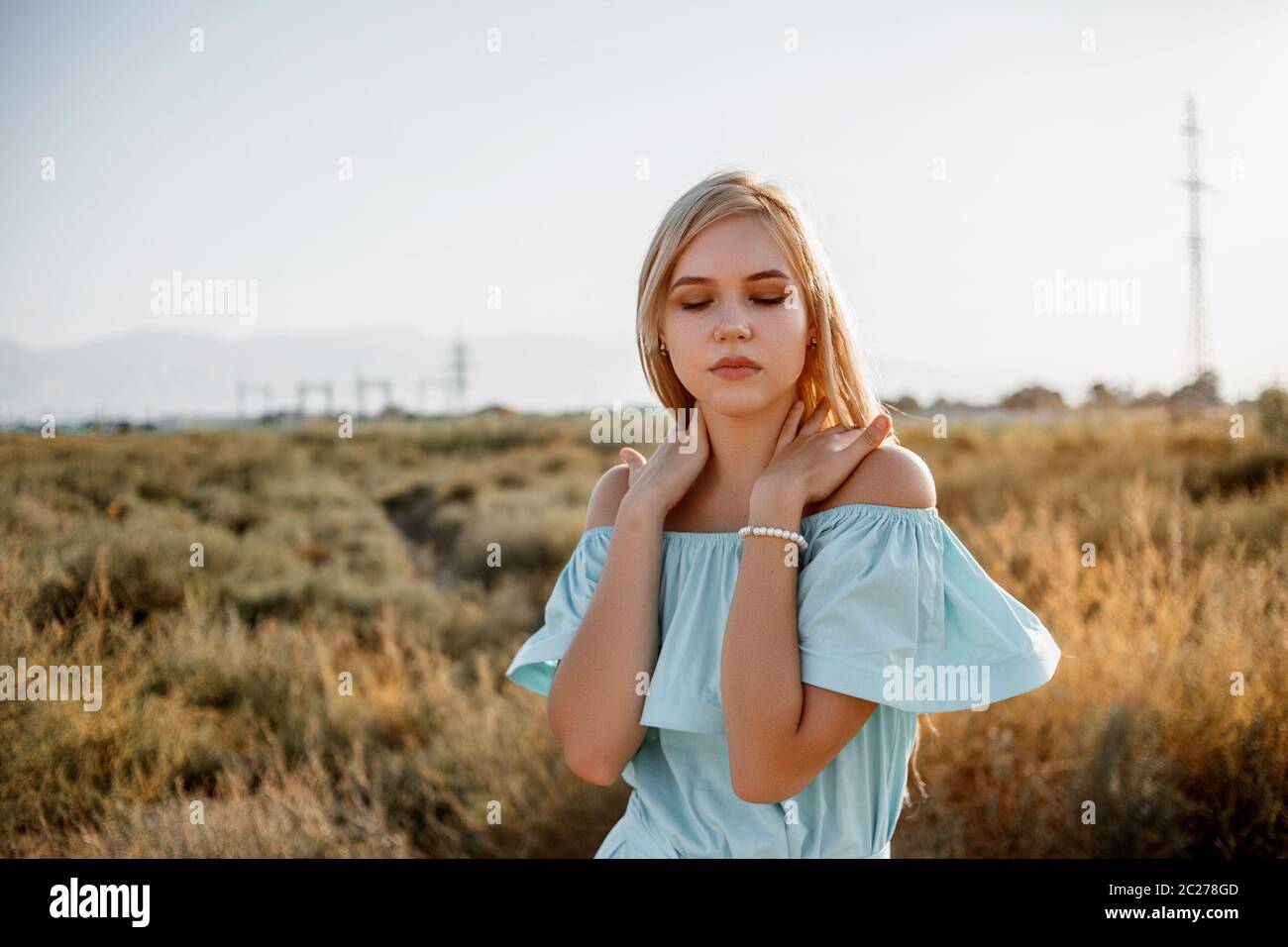portrait of young beautiful caucasian blonde girl in light blue dress ...