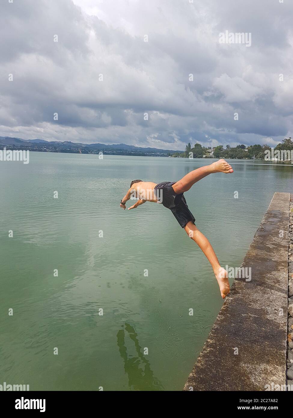 Mobile phone photo boy leaping into sea from edge. Stock Photo
